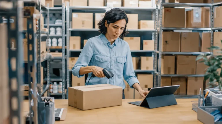 Employée réalisant un inventaire dans un entrepôt avec un scanner de codes-barres et une tablette